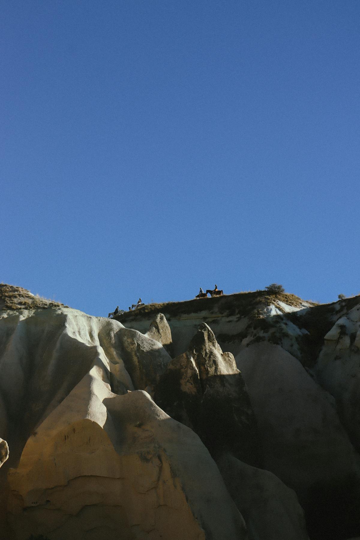 Horseback riding through mountain terrain, riders on trail through open meadow